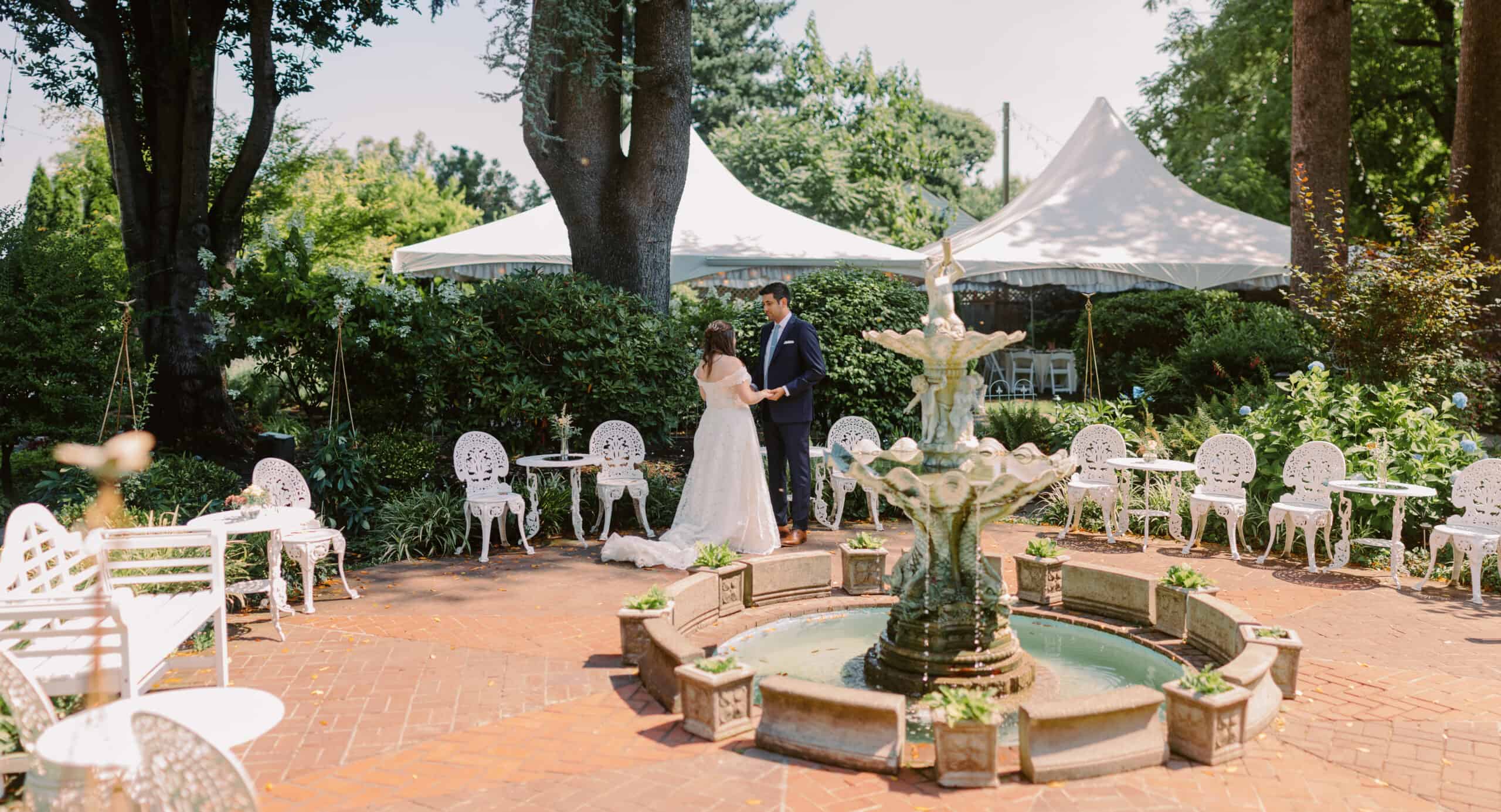 A bride and groom stand together by an antique fountain